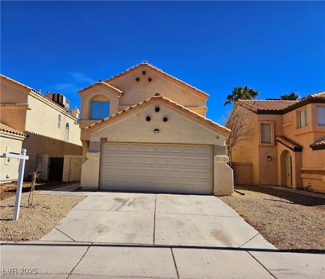 mediterranean / spanish house with a garage, concrete driveway, central AC, and stucco siding