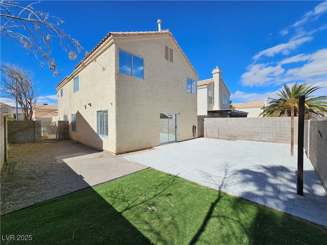 rear view of house featuring a patio area, a fenced backyard, and stucco siding