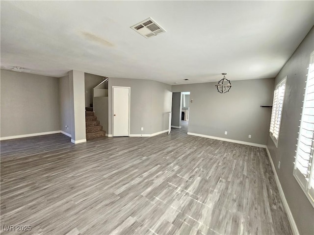 spare room featuring stairway, baseboards, visible vents, and wood finished floors