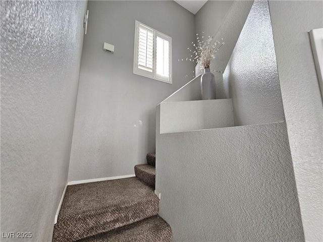 stairway with carpet floors, baseboards, and a textured wall