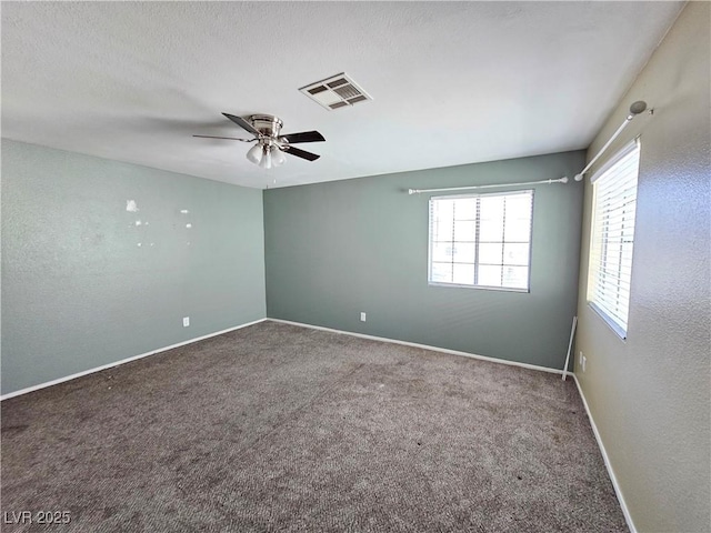 unfurnished room with a textured ceiling, a ceiling fan, visible vents, baseboards, and carpet