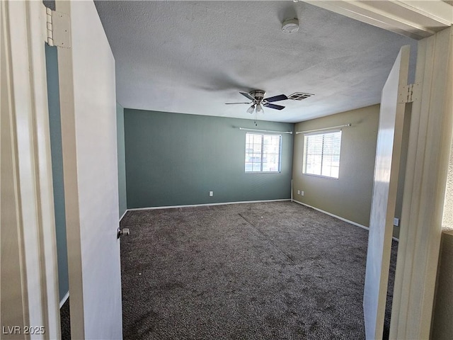 empty room featuring visible vents, carpet flooring, ceiling fan, a textured ceiling, and baseboards