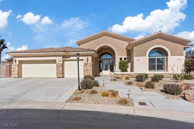 mediterranean / spanish-style house featuring a garage, driveway, stone siding, a tile roof, and stucco siding