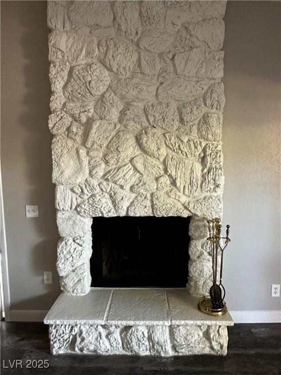 interior details with a stone fireplace, baseboards, and wood finished floors