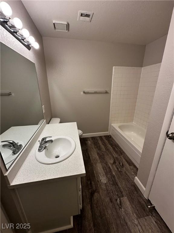 bathroom with baseboards, visible vents, wood finished floors, a textured ceiling, and vanity