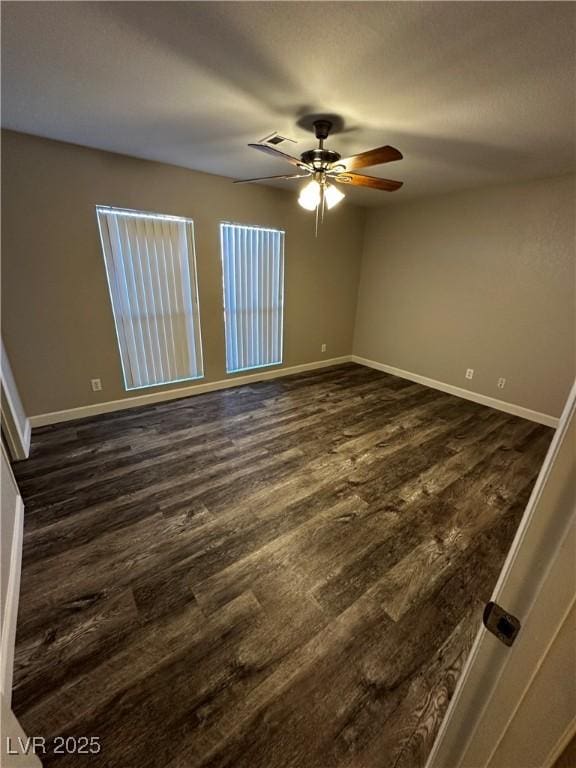 empty room featuring dark wood-style floors, ceiling fan, and baseboards