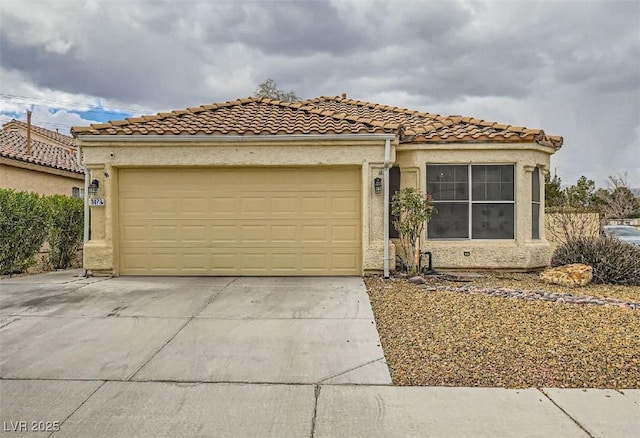 mediterranean / spanish-style house with concrete driveway, a tile roof, an attached garage, and stucco siding