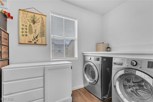 washroom with cabinet space, washing machine and clothes dryer, and wood finished floors