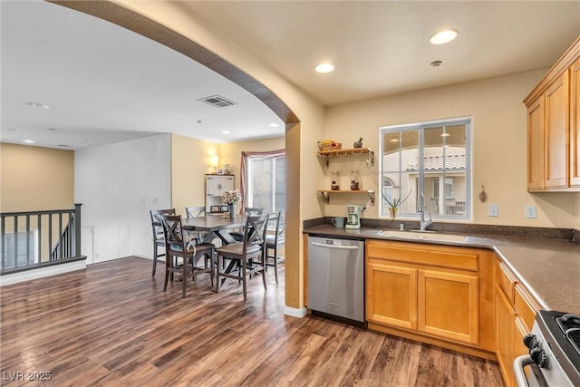 kitchen with arched walkways, stainless steel appliances, visible vents, a sink, and wood finished floors