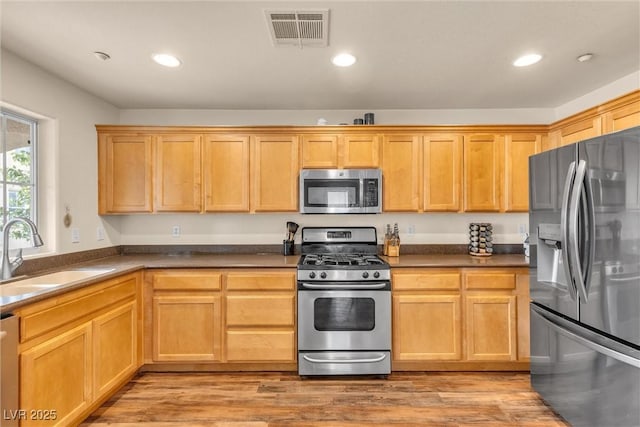 kitchen featuring stainless steel appliances, a sink, visible vents, and recessed lighting