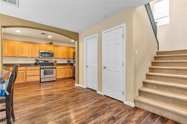 kitchen featuring dark countertops, dark wood-style floors, visible vents, and appliances with stainless steel finishes