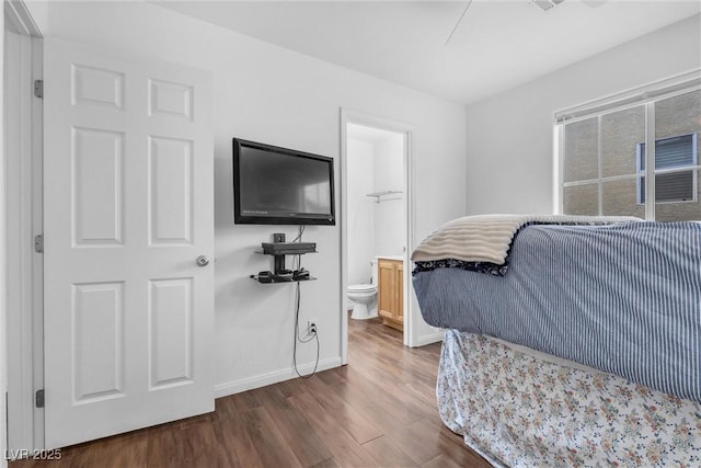 bedroom with connected bathroom, baseboards, and wood finished floors