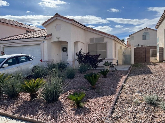 mediterranean / spanish-style home with an attached garage, fence, a gate, and stucco siding