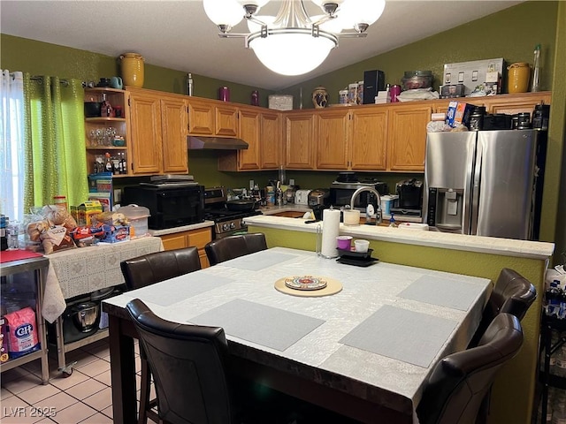 kitchen featuring a notable chandelier, light tile patterned floors, light countertops, appliances with stainless steel finishes, and under cabinet range hood