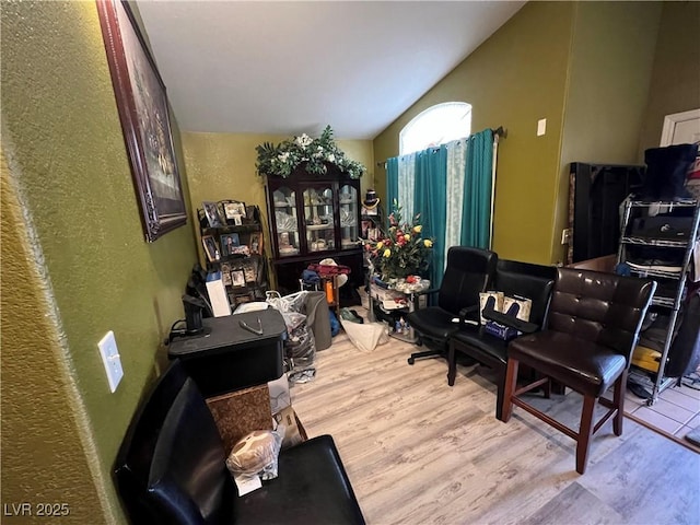 home office with vaulted ceiling, wood finished floors, and a textured wall