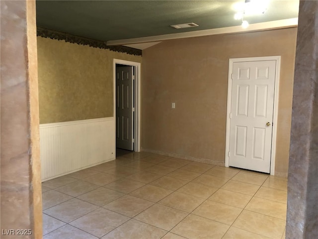 empty room with light tile patterned floors and wainscoting