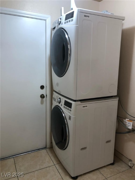 clothes washing area featuring light tile patterned floors, laundry area, and stacked washing maching and dryer