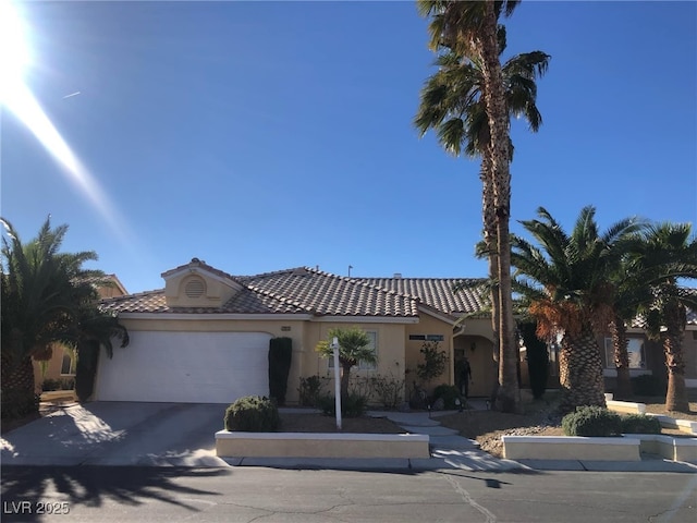 view of front of home with a tiled roof, a garage, driveway, and stucco siding