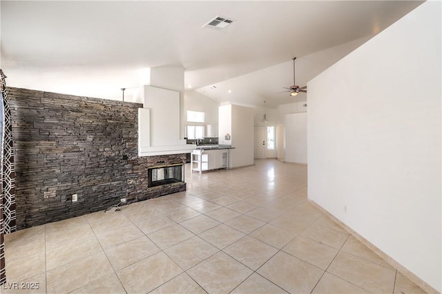 7613 Falconwing Ave, Las Vegas, NV 89131 - unfurnished living room featuring vaulted ceiling, light tile patterned floors, ceiling fan, and a stone fireplace
