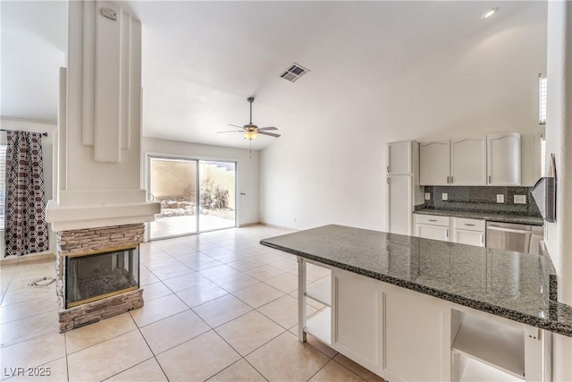 7613 Falconwing Ave, Las Vegas, NV 89131 - kitchen with dark stone counters, ceiling fan, a peninsula, decorative backsplash, and white cabinetry