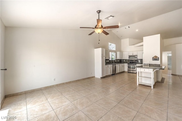 7613 Falconwing Ave, Las Vegas, NV 89131 - kitchen featuring stainless steel appliances, light tile patterned flooring, dark countertops, open shelves, and high vaulted ceiling