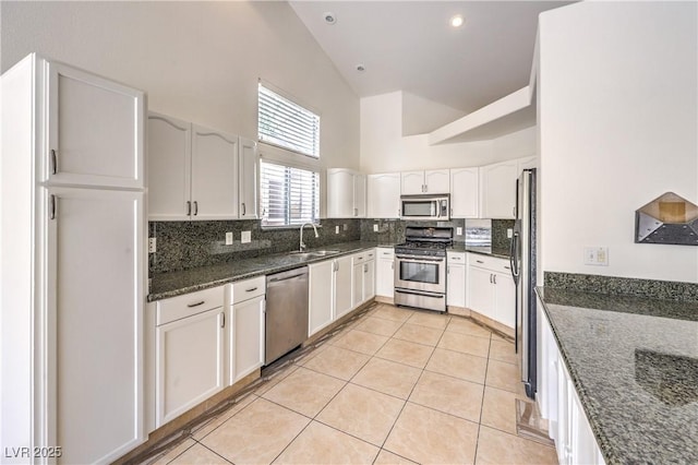 7613 Falconwing Ave, Las Vegas, NV 89131 - kitchen with appliances with stainless steel finishes, high vaulted ceiling, decorative backsplash, dark stone countertops, and light tile patterned flooring