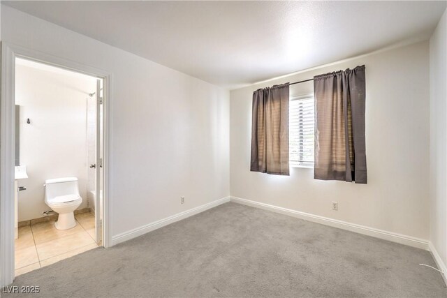 7613 Falconwing Ave, Las Vegas, NV 89131 - unfurnished bedroom with carpet flooring, baseboards, ensuite bathroom, and tile patterned floors