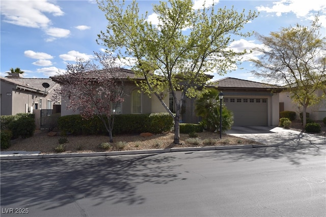 view of front facade featuring concrete driveway, a tiled roof, an attached garage, and stucco siding