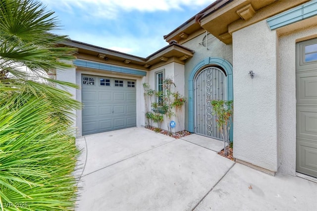 property entrance with stucco siding, concrete driveway, and an attached garage