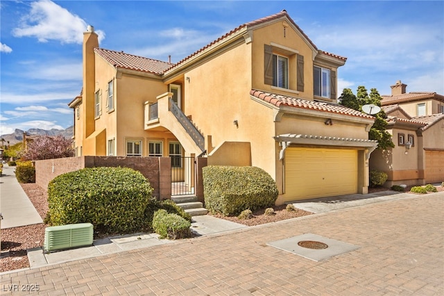 mediterranean / spanish-style home with stucco siding, decorative driveway, a chimney, and a gate