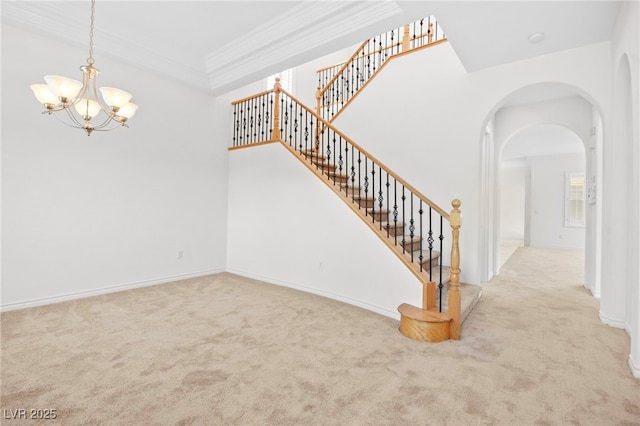 stairs with crown molding, baseboards, carpet flooring, arched walkways, and a notable chandelier