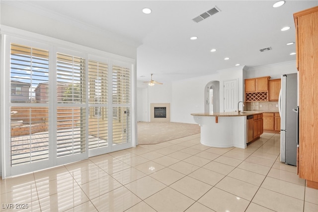 kitchen with visible vents, crown molding, ceiling fan, freestanding refrigerator, and a glass covered fireplace