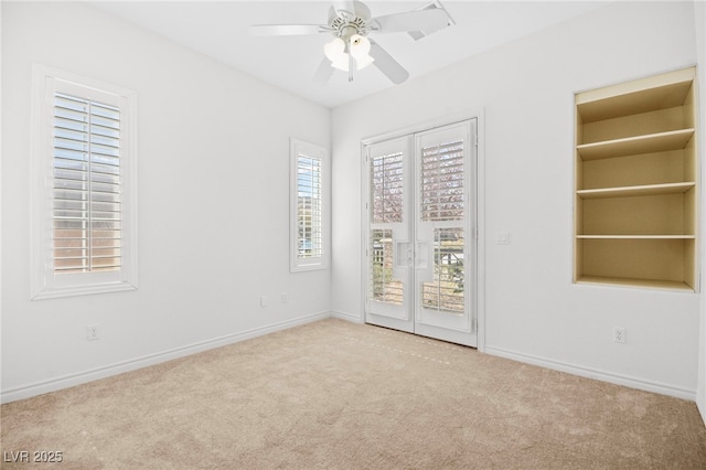 carpeted empty room with a ceiling fan and baseboards