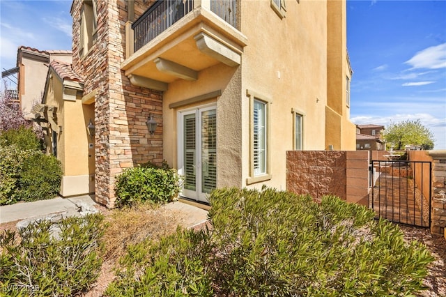 property entrance with stucco siding, a balcony, and fence