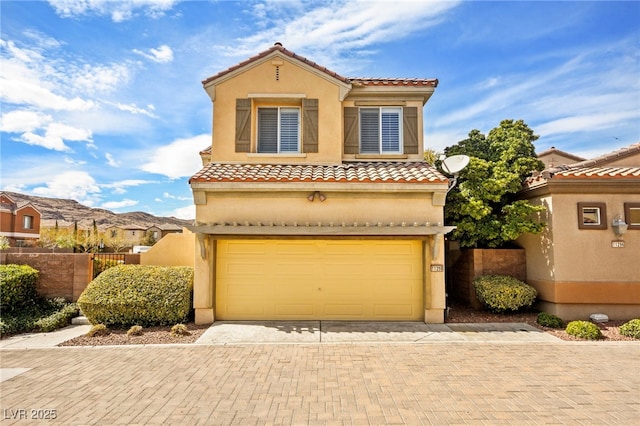 mediterranean / spanish-style home with decorative driveway, fence, a garage, and stucco siding