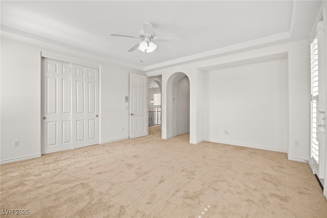 unfurnished bedroom with baseboards, arched walkways, and carpet flooring