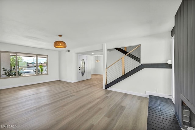 unfurnished living room with stairs, visible vents, wood finished floors, and baseboards