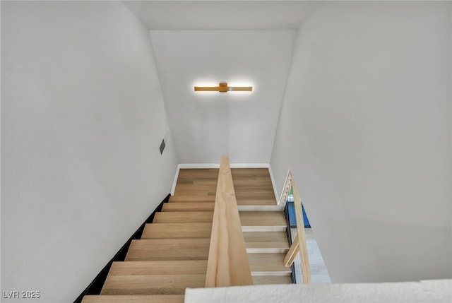 stairway featuring visible vents, baseboards, and wood finished floors