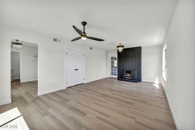 unfurnished living room featuring visible vents, ceiling fan with notable chandelier, light wood-style floors, a fireplace, and baseboards