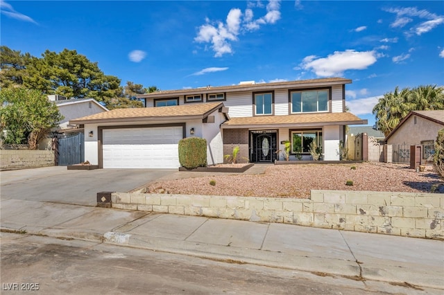 traditional-style home with a gate, fence, concrete driveway, an attached garage, and brick siding