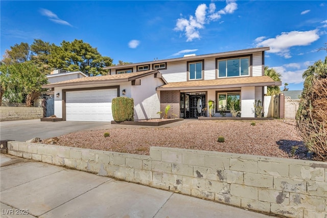 traditional home with brick siding, driveway, an attached garage, and fence