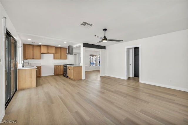 kitchen with visible vents, wall chimney range hood, open floor plan, gas stove, and a sink