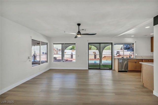 interior space featuring visible vents, baseboards, light wood-style floors, and a sink