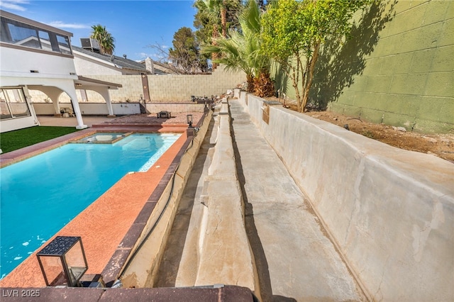 view of swimming pool featuring a patio, a fenced backyard, and a pool with connected hot tub