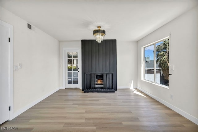 unfurnished living room with visible vents, a fireplace, baseboards, and light wood-style floors