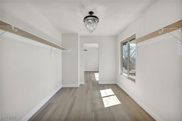 walk in closet with an inviting chandelier and wood finished floors