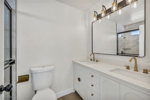 bathroom featuring double vanity, toilet, a tile shower, and a sink