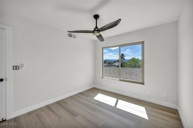 spare room featuring a ceiling fan, wood finished floors, visible vents, and baseboards