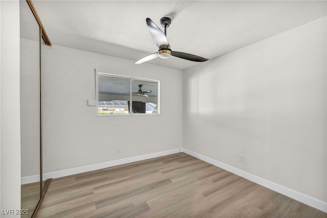 empty room with ceiling fan, baseboards, and wood finished floors