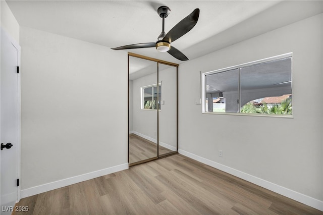 unfurnished bedroom featuring wood finished floors, baseboards, a closet, and ceiling fan